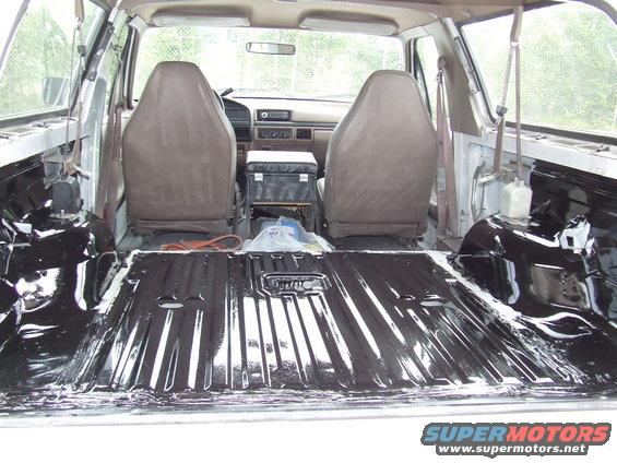 Interior of a disassembled vehicle with exposed metal floor and two front seats