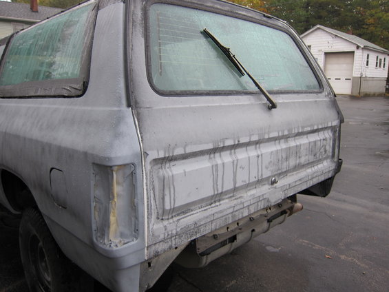 Rear view of a grey SUV with a dirty windshield and missing taillight