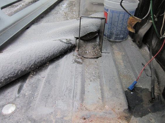 Dusty metal floor with a bracket and a plastic cup with markings