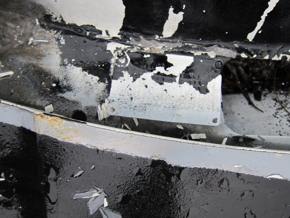 Close-up of peeling paint and rust on a metal surface, possibly a vehicle part