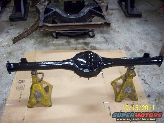 Black painted rear axle assembly resting on yellow jack stands