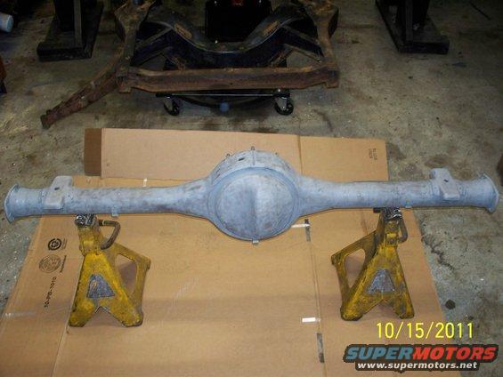 Rear axle assembly on jack stands, with a vehicle frame in the background