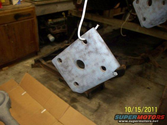 Metal bracket with multiple holes, painted light blue and brown, hanging from a wire