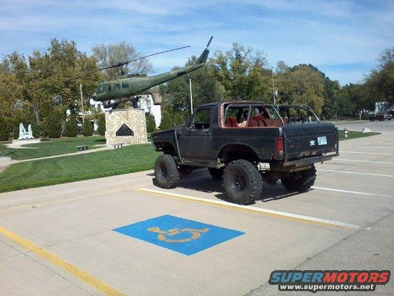 Black lifted Ford Bronco with a roll cage, parked in a handicapped spot