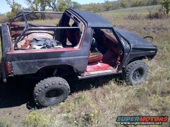 Modified Ford Bronco with roll cage, doors removed, and off-road tires