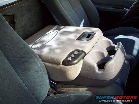 Interior shot of a truck's center console with cup holders and buttons, next to the driver's seat
