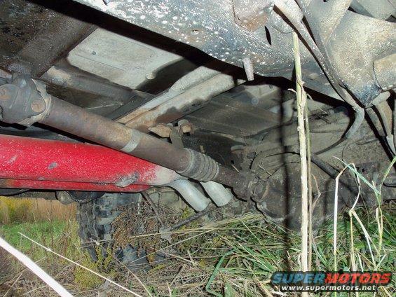 Underside view of a vehicle's drivetrain with a red component and exhaust pipes visible