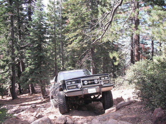 Black off-road SUV with aftermarket grille guard and large tires navigating a rocky trail