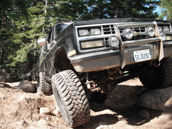 Black SUV with lifted suspension and large tires on a rocky trail