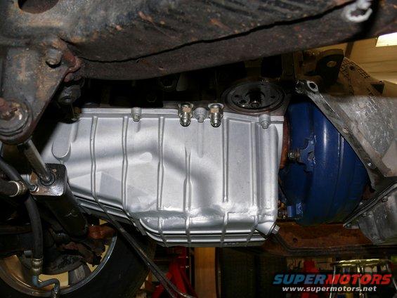 Underside view of a vehicle showing a silver oil pan and part of the transmission