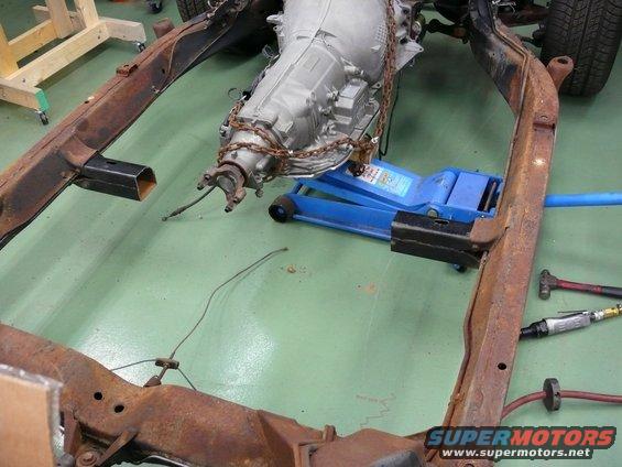 Car frame with transmission on a blue jack, tools nearby