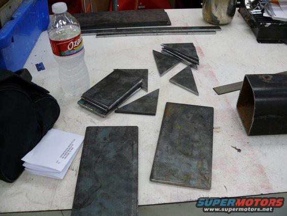 Metal plates and triangles scattered on a workbench with a bottle of Ozarka water