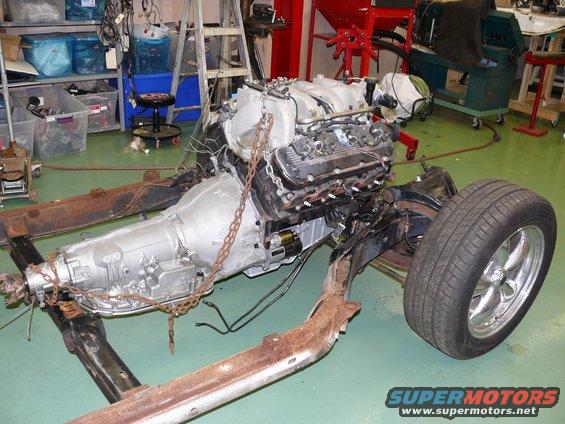 Vehicle chassis with engine and transmission assembly hanging from chains, with one wheel attached