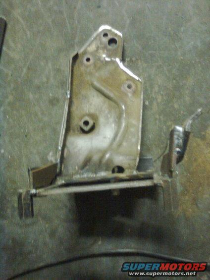 Metal bracket with welded extensions and mounting holes on a workshop floor