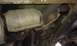 1984 Ford Bronco - The catalytic converter and exhaust pipes are shown from underneath the vehicle, with signs of rust on the metal parts.