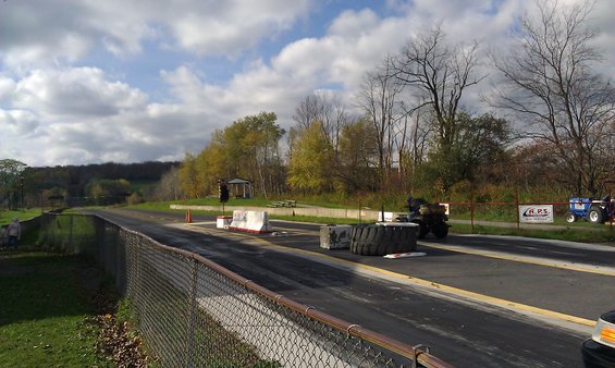 Drag strip with a tractor and ATV, trees in background, cloudy sky