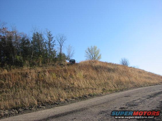 1991 Ford Bronco parked on a dry, grassy hill under a clear blue sky