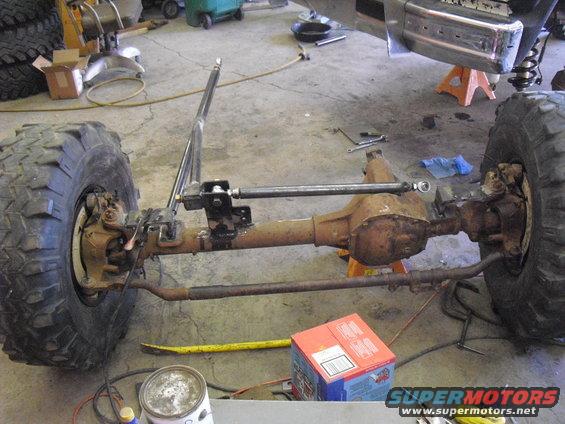 off-road vehicle front axle assembly with large tires and suspension components, in a garage