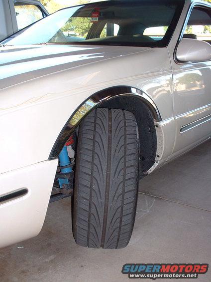 White car's front tire and blue suspension components visible
