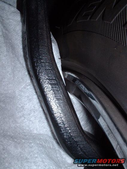 Close-up of a black suspension component next to a tire and rim