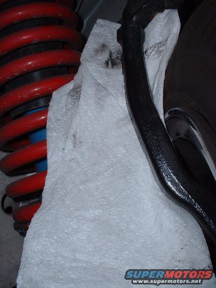 Black suspension component and red coilover shock absorber with blue accents, partially covered by a paper towel