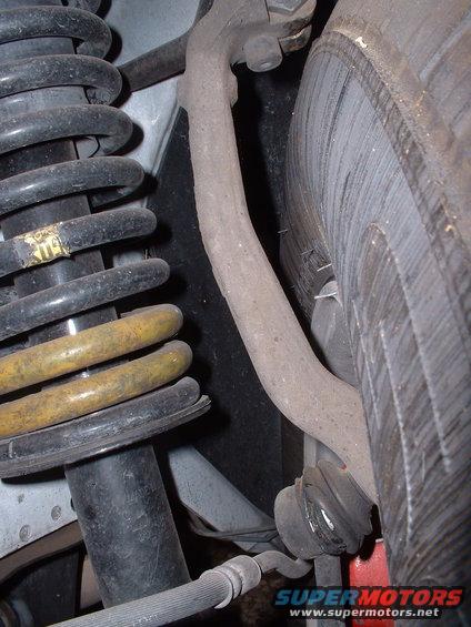 Car suspension with black and yellow springs, shock absorber, and control arm near a tire
