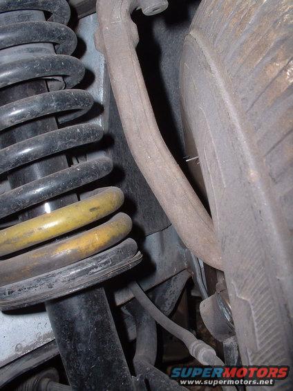 Close-up of a car's suspension system, showing a coil spring and control arm