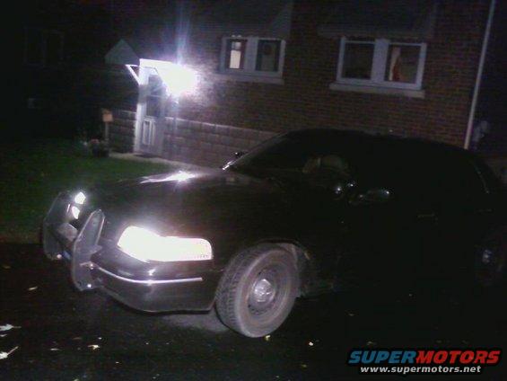 Black 1998 Ford Crown Victoria with a push bar, parked at night