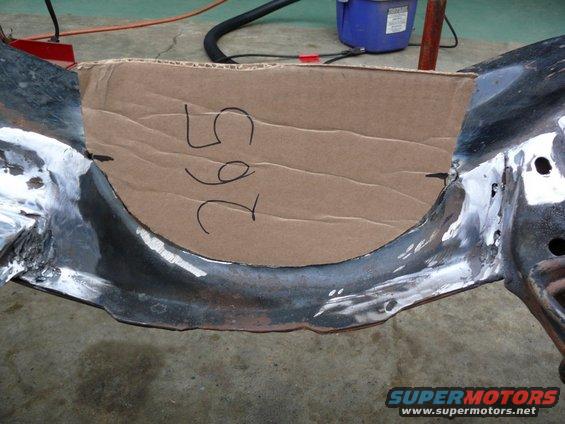 Close-up of a car frame section with a cardboard template marked '265' placed over it