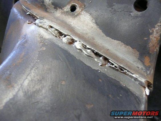 Close-up of a crudely welded metal component with visible rust and rough texture