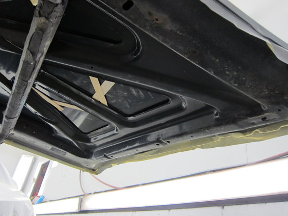 underside of a car hood with tape and some wooden wedges