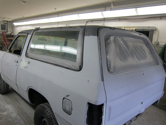 White pickup truck body in primer, rear 3/4 view. Windows taped off for painting