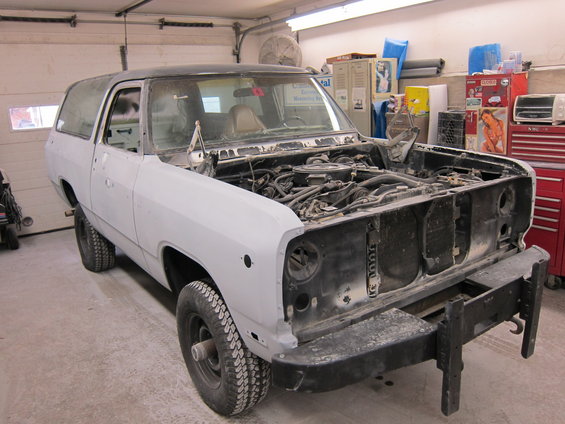 Light gray SUV with hood open, undergoing repairs in a garage