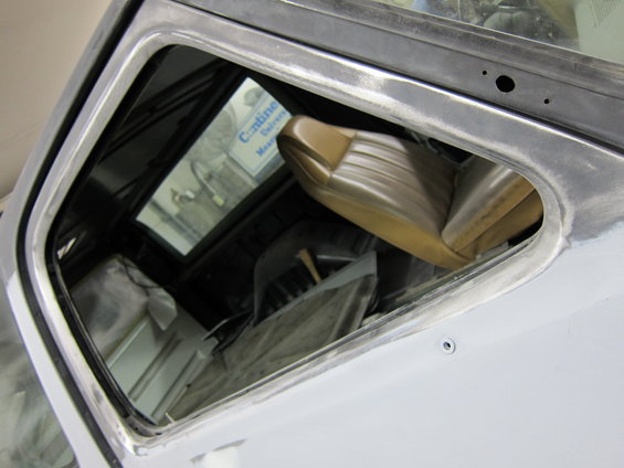 Tan vinyl seat and interior of a truck undergoing bodywork, viewed through an open window