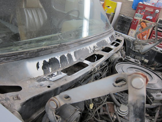 Engine bay and windshield cowl of a vehicle with peeling paint