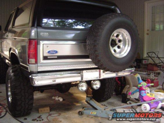 Gray 1986 Ford Bronco rear with spare tire, chrome bumper, and dual exhaust