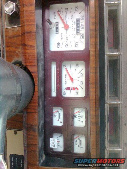 Dashboard gauges with woodgrain trim, showing speedometer, tachometer, fuel, temperature, and oil pressure