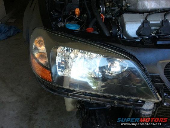 Close-up of a car's front headlight assembly and part of the engine bay. Text on headlight reads 'STANLEY'