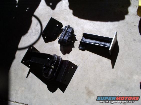 Three black engine mounts on a concrete surface