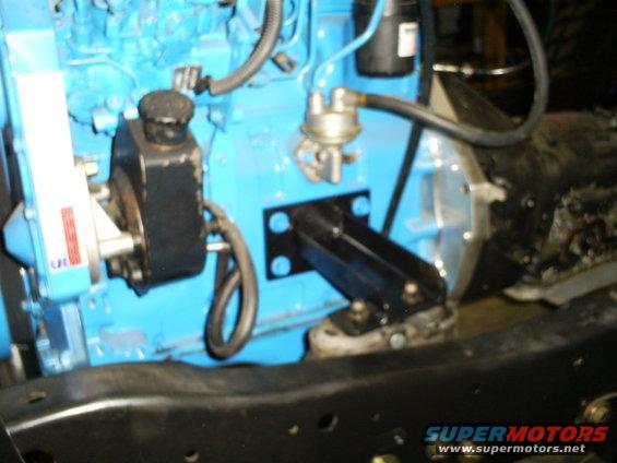 Close-up of a blue engine block with a black power steering pump and fuel pump attached