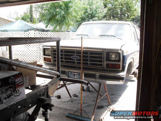Front of a 1986 Ford Bronco on jack stands, showing grille and headlights