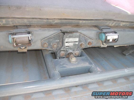 Seatbelt retractors and roll cage mounting hardware on a metal floor