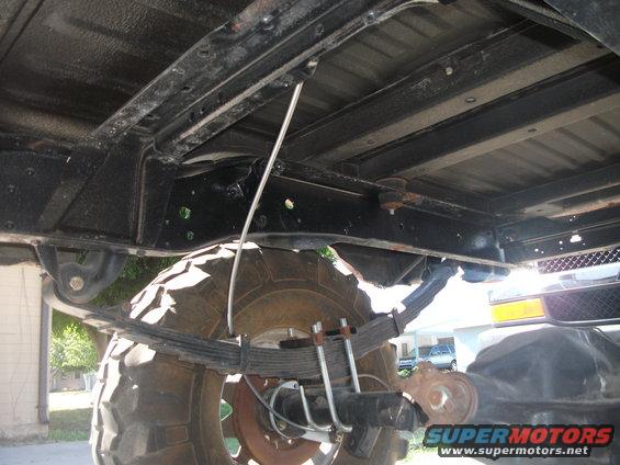 Undercarriage of a vehicle with large tires, showing leaf springs and frame