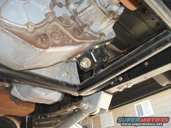 Underside view of a vehicle's transmission and transfer case with visible rust and aftermarket modifications