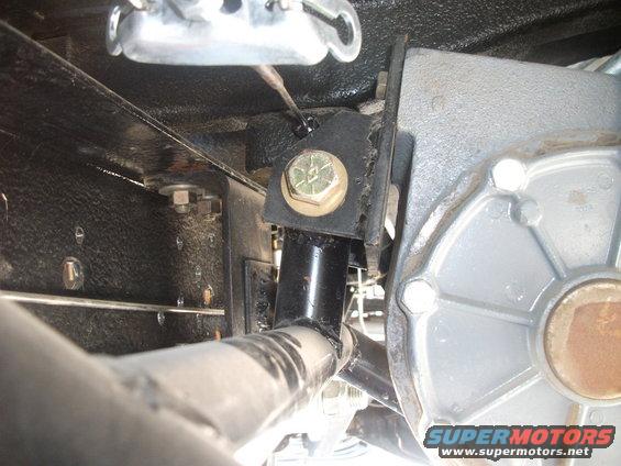 Close-up of a transfer case mounting bracket with bolts and a black support tube