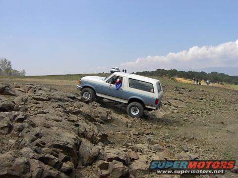 White and blue Ford Bronco climbing rocky terrain