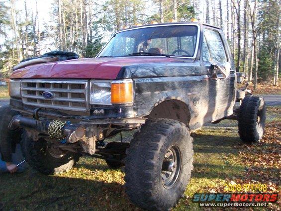 Modified Ford pickup truck with large tires and lifted suspension, front view