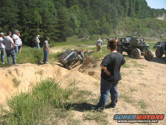 Off-road vehicles navigating a dirt track with one vehicle tilted in a ditch