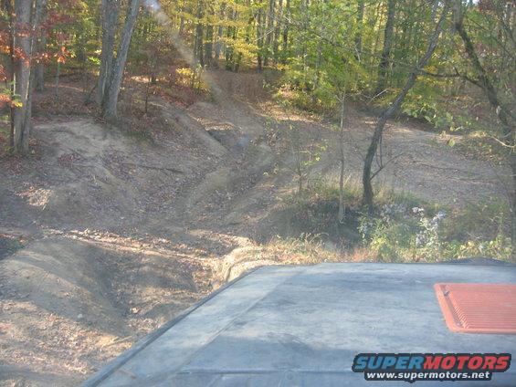 Off-road trail in woods with part of a vehicle roof in foreground