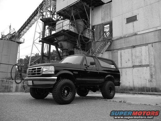 Black Ford Bronco with lifted suspension and off-road tires parked in front of an industrial building